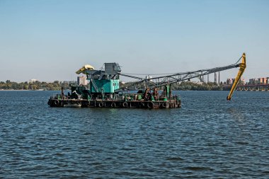Dredger nehirde. Nehrin dibini temizliyorum. Nehir akışını muhafaza et. Doğa, nehir, gökyüzü, bulutlar.