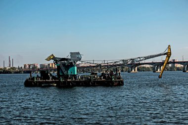 Dredger nehirde. Nehrin dibini temizliyorum. Nehir akışını muhafaza et. Doğa, nehir, gökyüzü, bulutlar.
