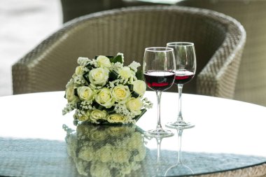 Gözlüklü kırmızı şarap ve sarı-beyaz güller. Yaz tatili. Düğün kartı. Davet kavramı.