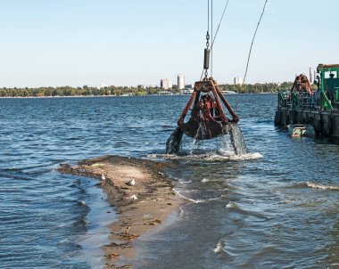 Yeni kurulan adayı Dnieper Nehri 'ndeki endüstriyel atıklardan temizliyorum. Modern nehirlerin çevresel sorunları. Ekoloji kavramı.