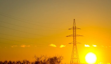 Güç iletim kuleleri veya altın gökyüzü ve bulutlu elektrik direkleri. Gün batımında elektrik hattı olan siluetli elektrik direği..