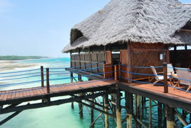 Ahşap iskele ve Zanzibar Adası tropik bir plajda thatched çatı.