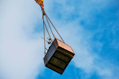 Mavi gökyüzüne karşı uzun sarı bir bumbası olan yüksek binalı bir vinç..