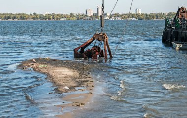 Özel bir tarağın kovası yapay adayı temizler. Dinyeper Nehri 'nin kıyı sularında ekolojik felaket.
