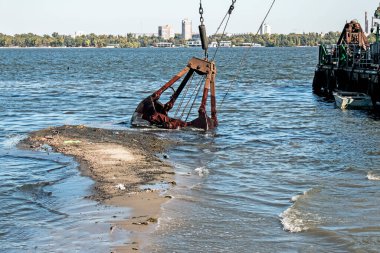 Özel bir tarağın kovası yapay adayı temizler. Dinyeper Nehri 'nin kıyı sularında ekolojik felaket.
