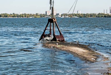 Özel bir tarağın kovası yapay adayı temizler. Dinyeper Nehri 'nin kıyı sularında ekolojik felaket.