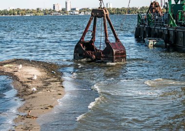 Özel bir tarağın kovası yapay adayı temizler. Dinyeper Nehri 'nin kıyı sularında ekolojik felaket.