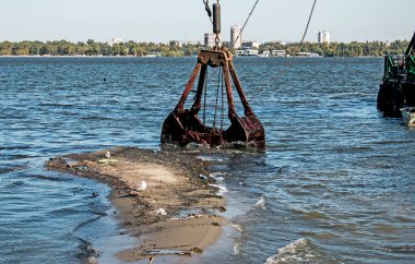 Özel bir tarağın kovası yapay adayı temizler. Dinyeper Nehri 'nin kıyı sularında ekolojik felaket.