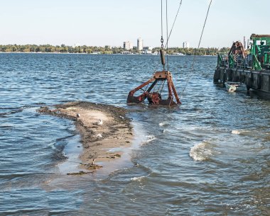 Özel bir tarağın kovası yapay adayı temizler. Dinyeper Nehri 'nin kıyı sularında ekolojik felaket.