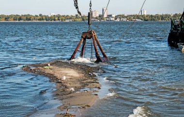 Özel bir tarağın kovası yapay adayı temizler. Dinyeper Nehri 'nin kıyı sularında ekolojik felaket.