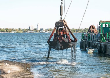 Özel bir tarağın kovası yapay adayı temizler. Dinyeper Nehri 'nin kıyı sularında ekolojik felaket.