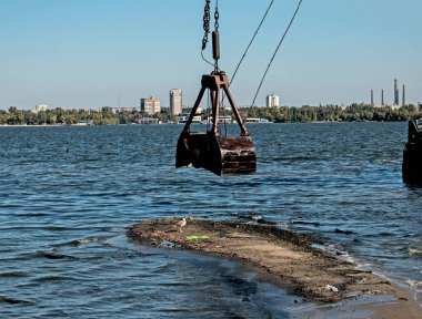 Özel bir tarağın kovası yapay adayı temizler. Dinyeper Nehri 'nin kıyı sularında ekolojik felaket.