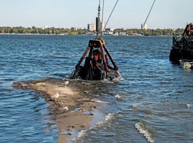 Özel bir tarağın kovası yapay adayı temizler. Dinyeper Nehri 'nin kıyı sularında ekolojik felaket.