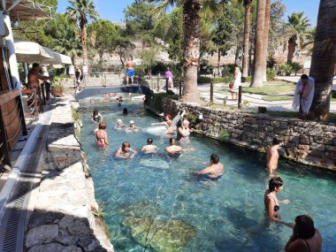 Pamukkale, Türkiye - Ekim 05, 2021: Antik Kleopatra 'nın havuzundaki insanlar modern Türkiye kenti Denizli yakınlarındaki Hierapolis antik kentinde termal suyla birlikte