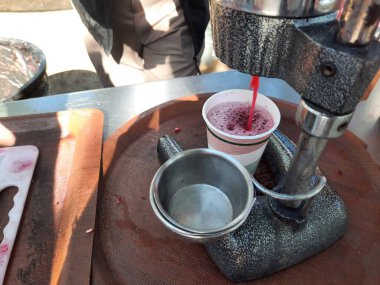 Meyve sıkacağı satıcısı. Güneşli bir günde, açık havada, sokak pazarında taze nar suyu yapıyor..