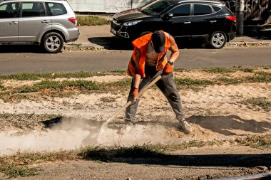 Dnepropetrovsk, Ukrayna - 09.15.2021: Turuncu üniformalı bir işçi inşaat enkazından tramvay raylarını temizliyor.