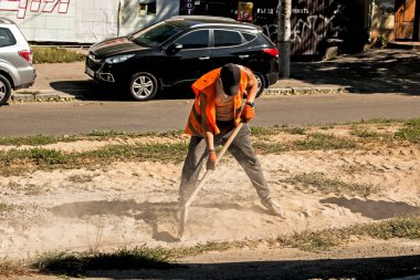 Dnepropetrovsk, Ukrayna - 09.15.2021: Turuncu üniformalı bir işçi inşaat enkazından tramvay raylarını temizliyor.