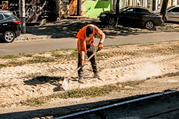 ウクライナのDnepropetrovsk 2021 オレンジの均一なシャベルを持つ労働者は 建設がれきから路面電車のレールをきれいにする — ストック写真