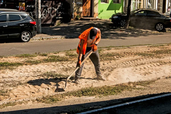 ウクライナのDnepropetrovsk 2021 オレンジの均一なシャベルを持つ労働者は 建設がれきから路面電車のレールをきれいにする — ストック写真
