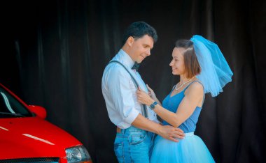 Evlilik yıldönümlerini kutlayan, düğün kıyafetli genç bir çiftin portresi. Çift arabayı yıkıyor. Gülümse, öp, sev.