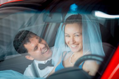 Evlilik yıldönümlerini kutlayan, düğün kıyafetli genç bir çiftin portresi. Çift arabayı yıkıyor. Gülümse, öp, sev.