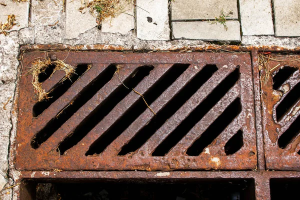 Yağmur suyu ya da erimiş kar almak için eski paslı bir rögar. Gri kaldırım levhalarının arka planında. Yukarıdan görüntüle