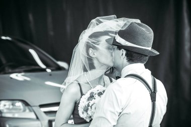 Evlilik yıldönümlerini siyah beyaz kutlayan düğün kıyafetli genç bir çiftin portresi. Gülümse, öp, buketi bir arada tut, aşkım.