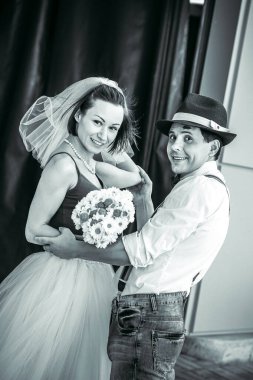 Evlilik yıldönümlerini siyah beyaz kutlayan düğün kıyafetli genç bir çiftin portresi. Gülümse, öp, buketi bir arada tut, aşkım.