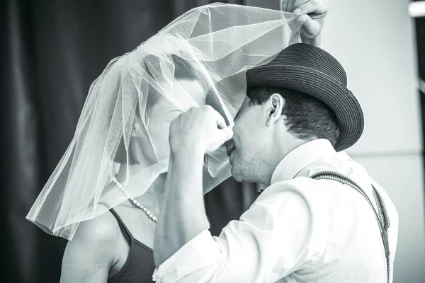 Evlilik yıldönümlerini siyah beyaz kutlayan düğün kıyafetli genç bir çiftin portresi. Gülümse, öp, buketi bir arada tut, aşkım.