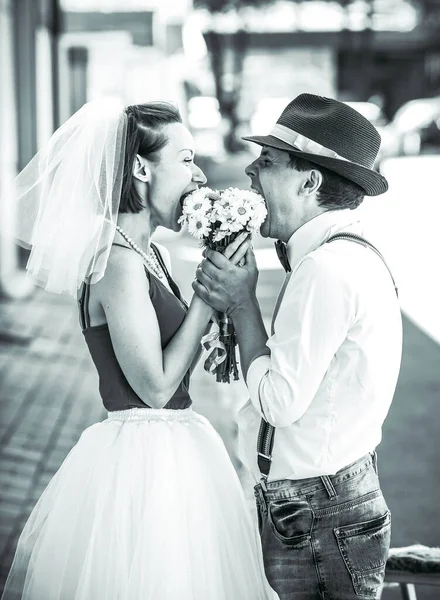 Evlilik yıldönümlerini siyah beyaz kutlayan düğün kıyafetli genç bir çiftin portresi. Gülümse, öp, buketi bir arada tut, aşkım.