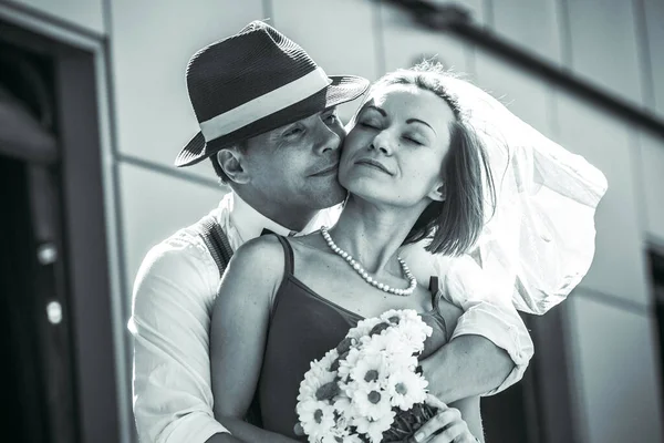 Evlilik yıldönümlerini siyah beyaz kutlayan düğün kıyafetli genç bir çiftin portresi. Gülümse, öp, buketi bir arada tut, aşkım.