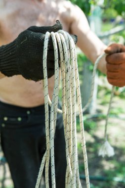 Yetişkin bir adam, kişisel bir entrikada inşaat işi için bir ip örer..