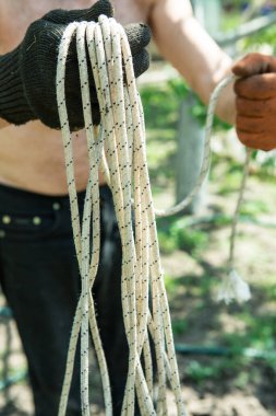 Yetişkin bir adam, kişisel bir entrikada inşaat işi için bir ip örer..