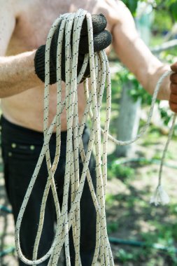 Yetişkin bir adam, kişisel bir entrikada inşaat işi için bir ip örer..
