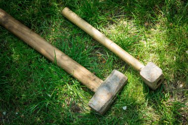 Close-up of two old hammers lying on green grass.