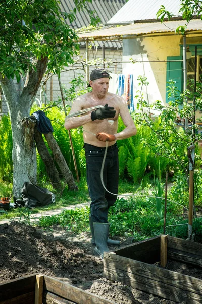 Yetişkin bir adam, kişisel bir entrikada inşaat işi için bir ip örer..