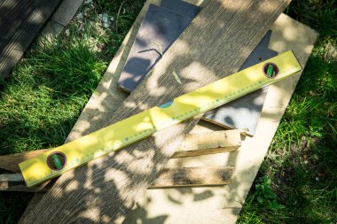 Çimlerin üzerinde bir set marangozluk aletleri var. Seviye, eski tahtalar.