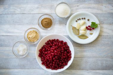 The process of making redcurrant sauce. Currant berries and spices are prepared in glass bowls.