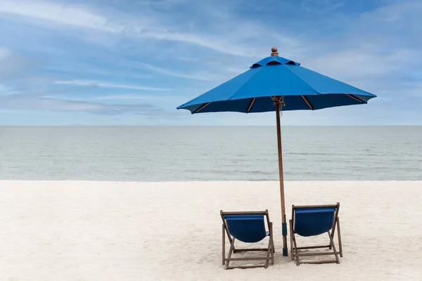 Cadeiras de praia azul e guarda-chuva com céu azul na praia na ilha tropical. — Fotografia de Stock