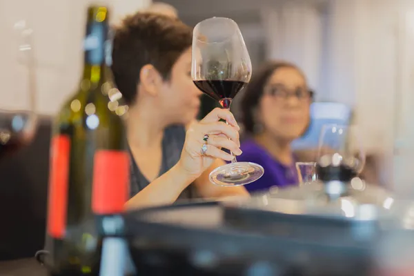 Женщина держит бокалы с красным вином во время еды с матерью. — стоковое фото