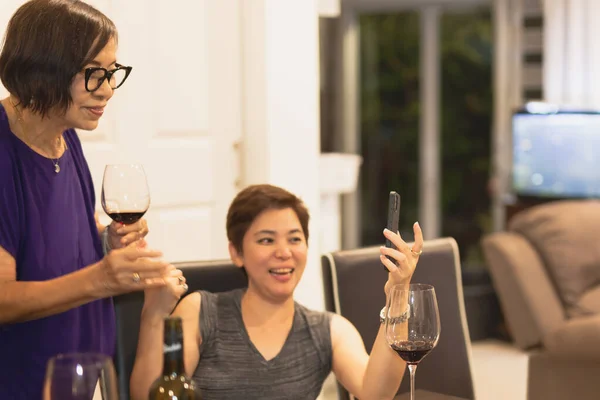 Selected focus happy woman with mother drinking red wine enjoy distant talk via video call.