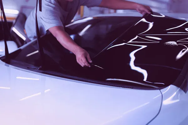 Специалист по автомобилям наносит тонировочную фольгу на стекло автомобиля в автосервисе. — стоковое фото