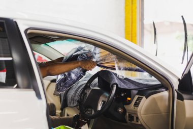 Adam uzman arabanın camındaki eski renkli filmi kaldırıyor..