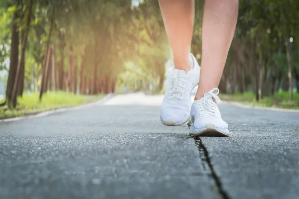Ejercicio femenino caminando por la calle en el parque con un primer plano en los zapatos para caminar. — Foto de Stock