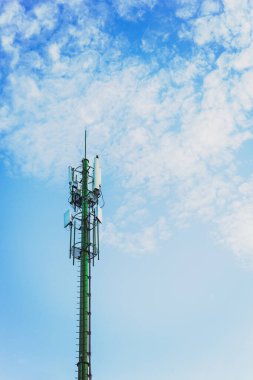 Mavi gökyüzü ve beyaz bulutlu telekomünikasyon kulesi dikey.