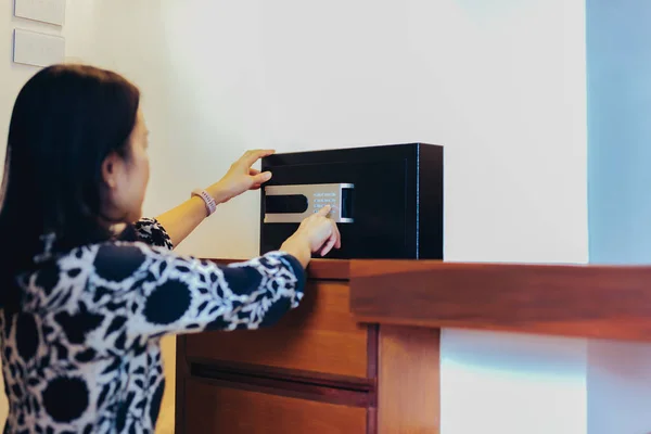 Mujer abriendo caja fuerte de acero negro con cerradura electrónica en habitación de hotel. — Foto de Stock