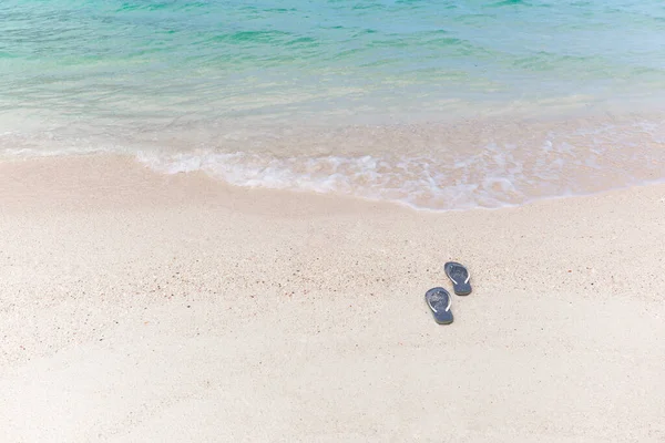 Chanclas de concepto de vacaciones tropicales en una playa de arena. — Foto de Stock