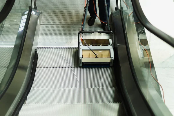 Reinigungskraft putzt Rolltreppe mit Mechanik in modernem Gebäude. — Stockfoto