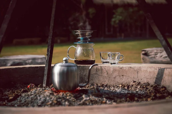 stock image Drip coffee equipment outdoor at camping with kettle on bonfire.