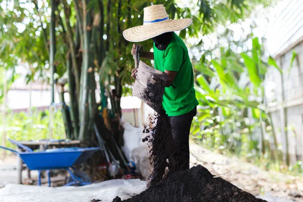 Hombre trabajador mezclando tierra fertilizante para plantación. — Foto de Stock